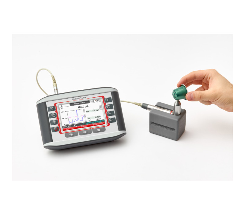 A 90 degree FH 4 sensor used in a stand measuring the thickness of an aluminium Nespresso cup with the online trend screen on the gauge, showing statistical graph and real time trend.